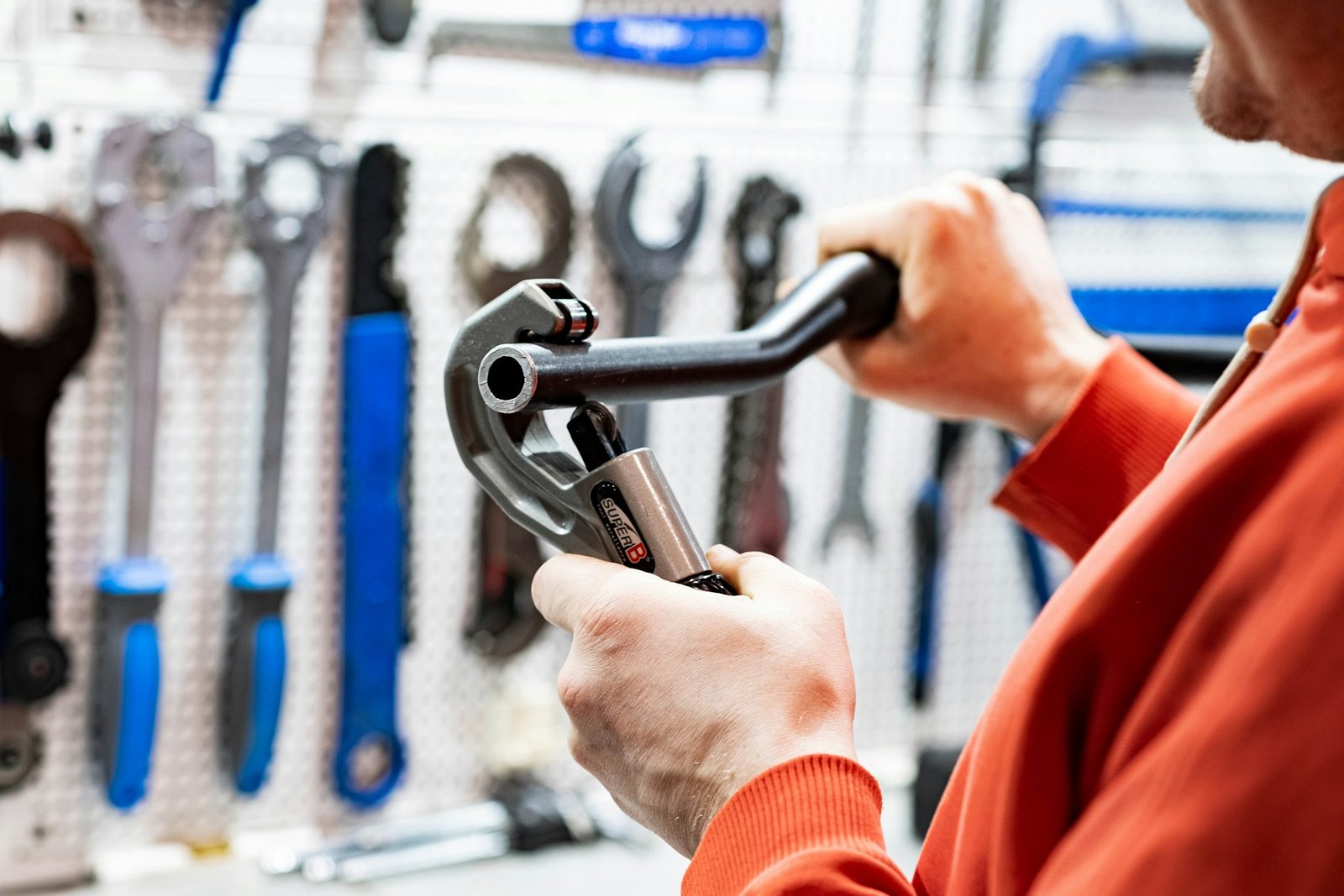 Contractor holding a wrench in front of a tool wall