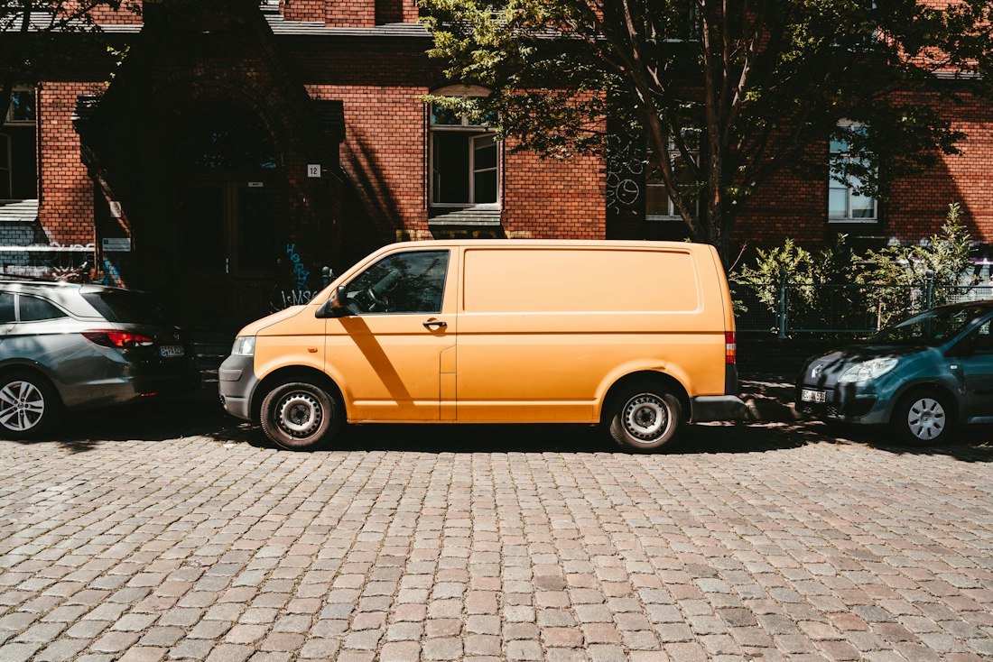 Yellow van parked beside brown brick building