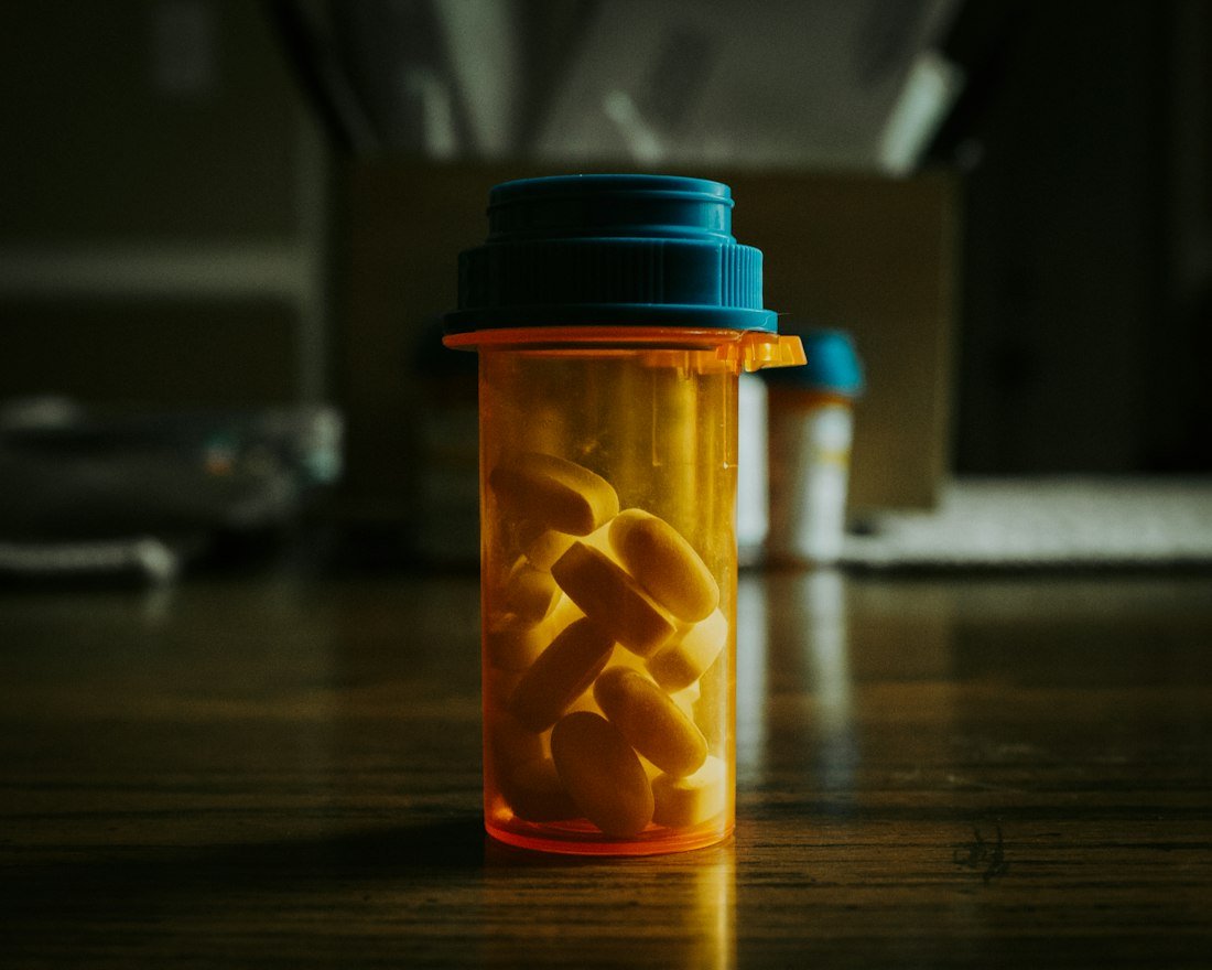 A bottle filled with pills sitting on top of a wooden table
