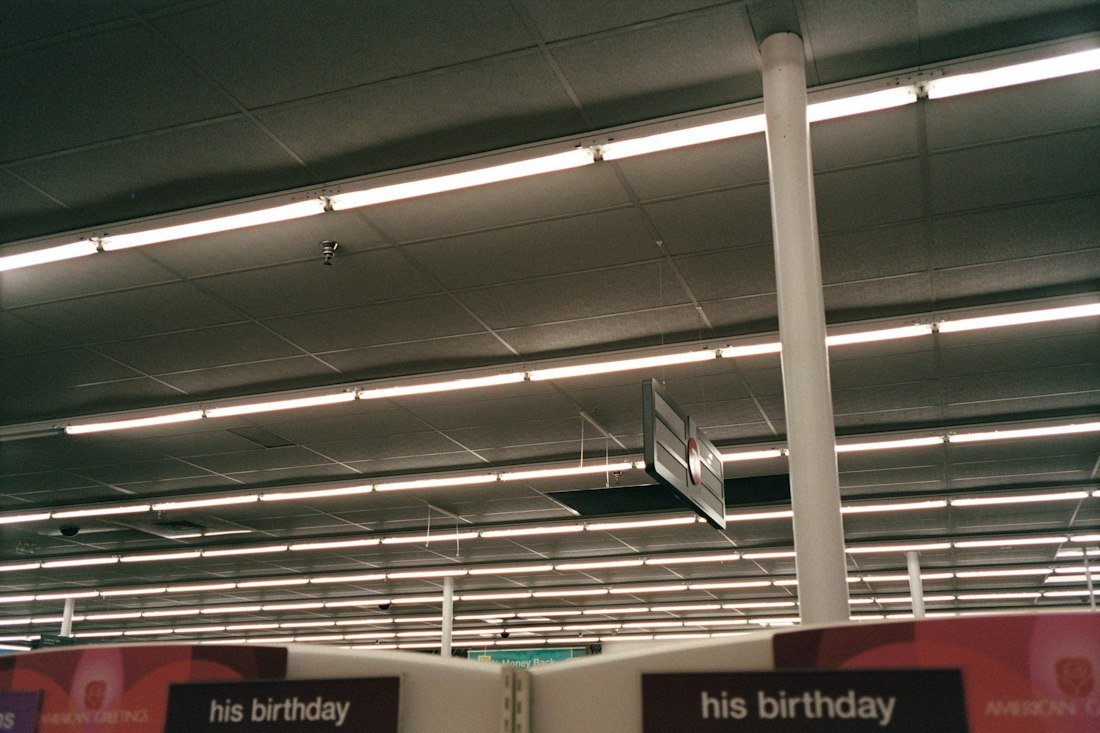 Fluorescent lights illuminate a retail store ceiling with signs