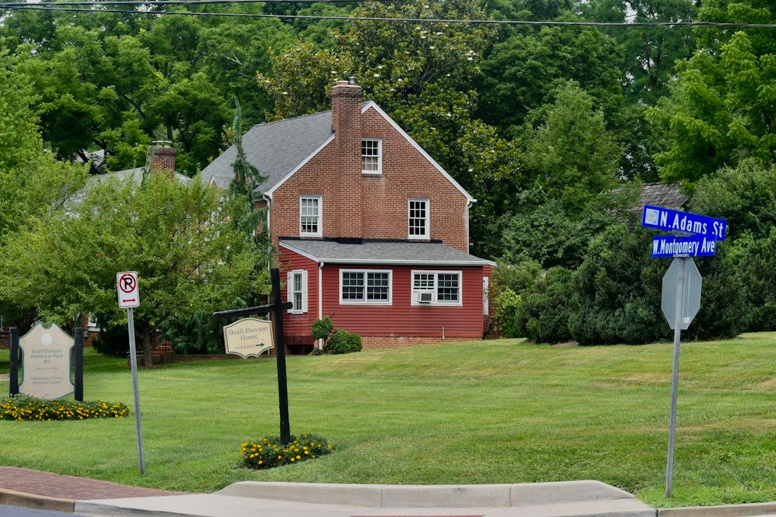 A red house with a blue street sign in front of it