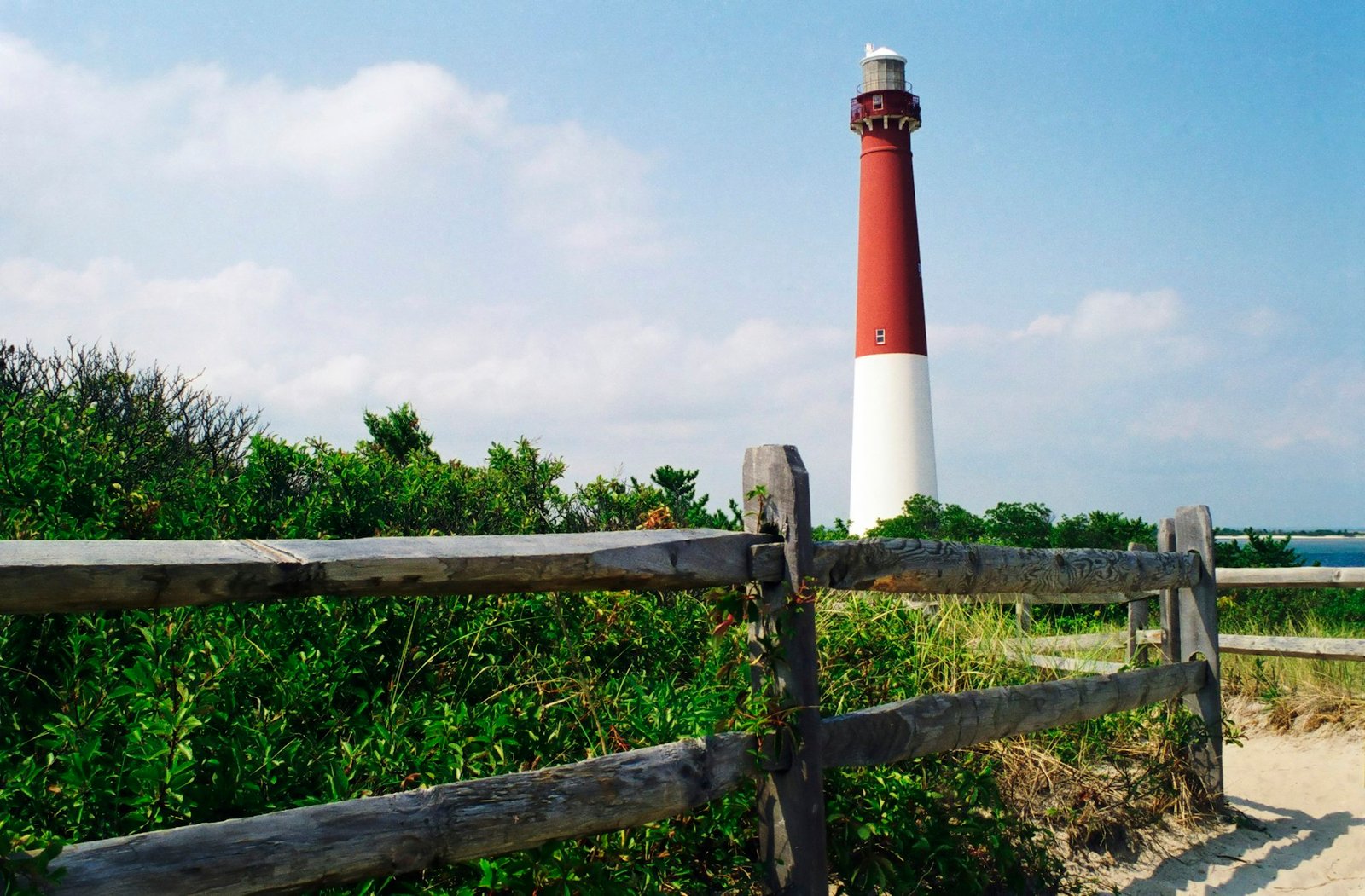 A red and white light house next to a wooden fence