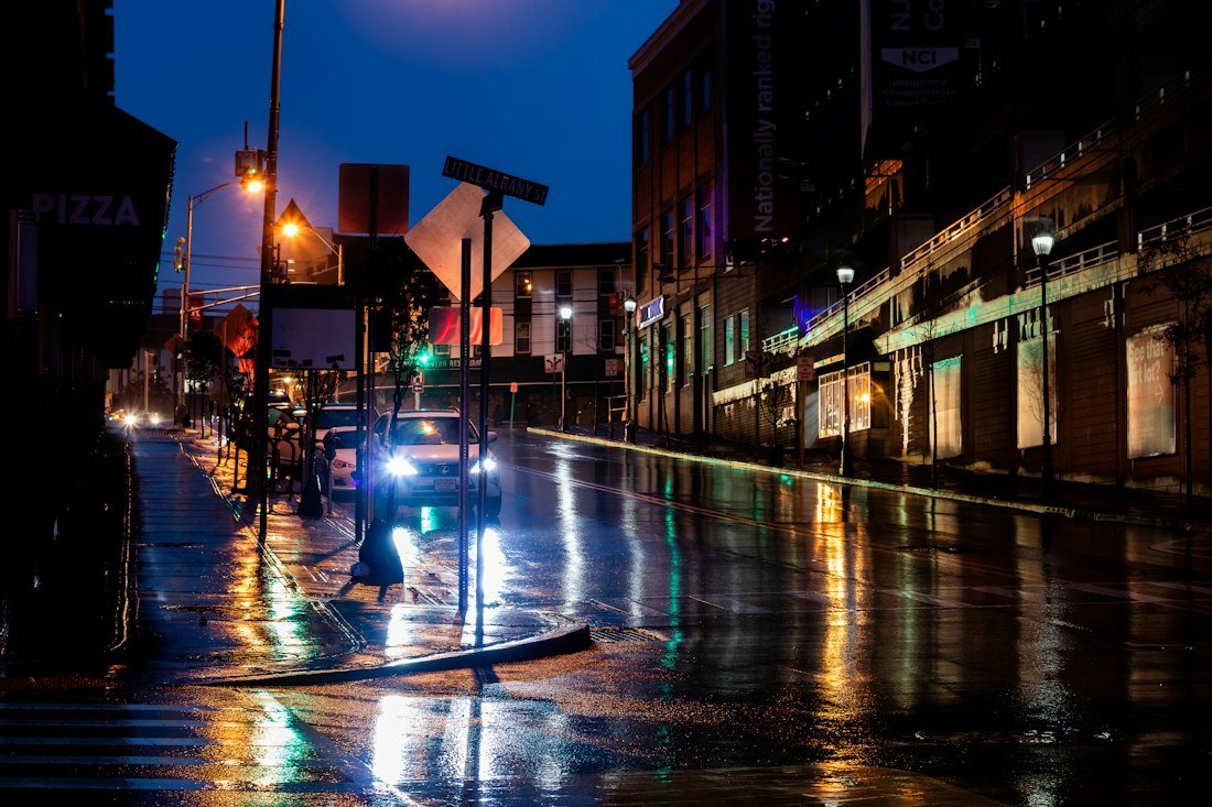 A city street at night with a car parked on the side of the road
