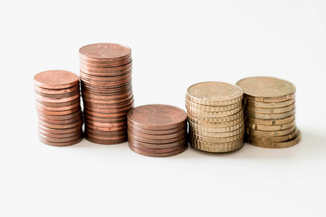 Stacked round gold-colored coins on white surface