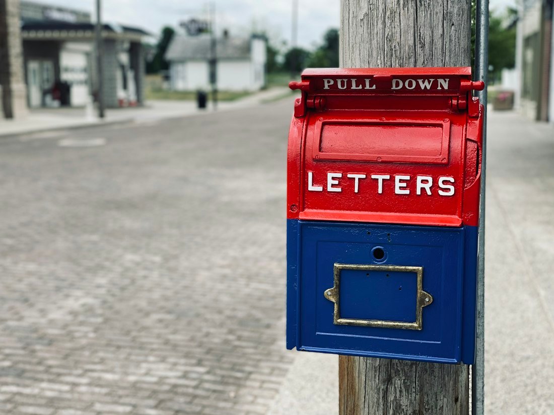 Red mail box on brown wooden post