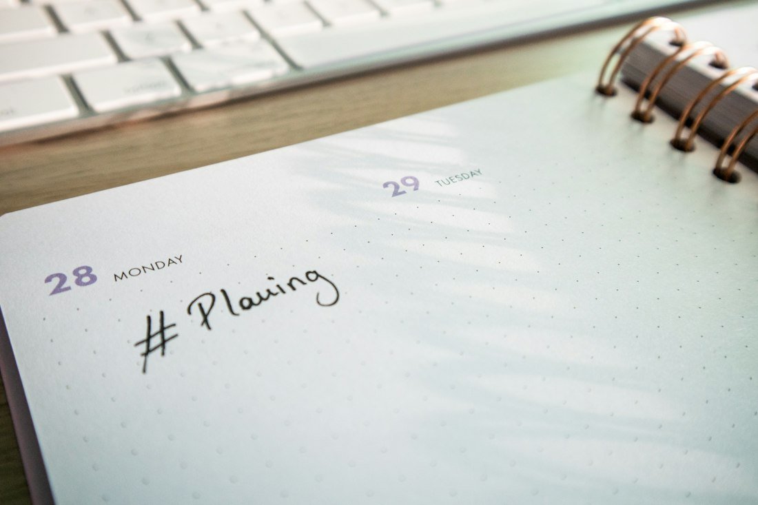 A notepad with a planner and a keyboard in the background
