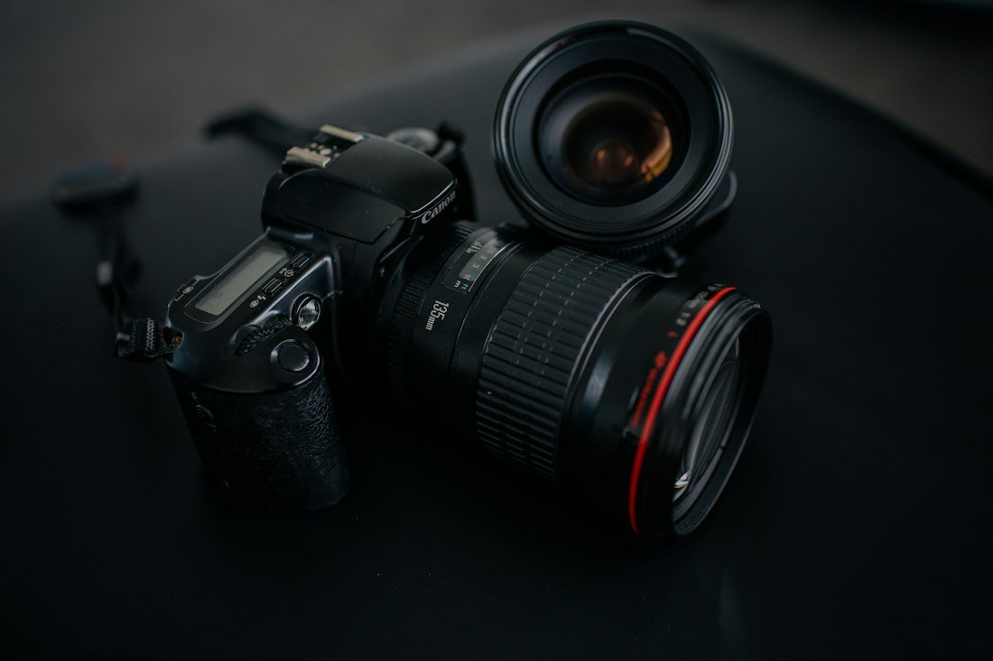 Black Canon DSLR camera beside camera lens