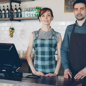 Two people serving customers behind a shop counter